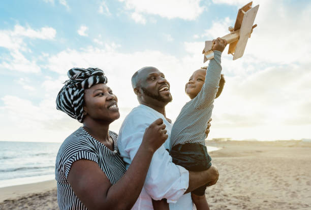 Happy African family having fun on the beach during summer vacation - Parents love and unity concept
